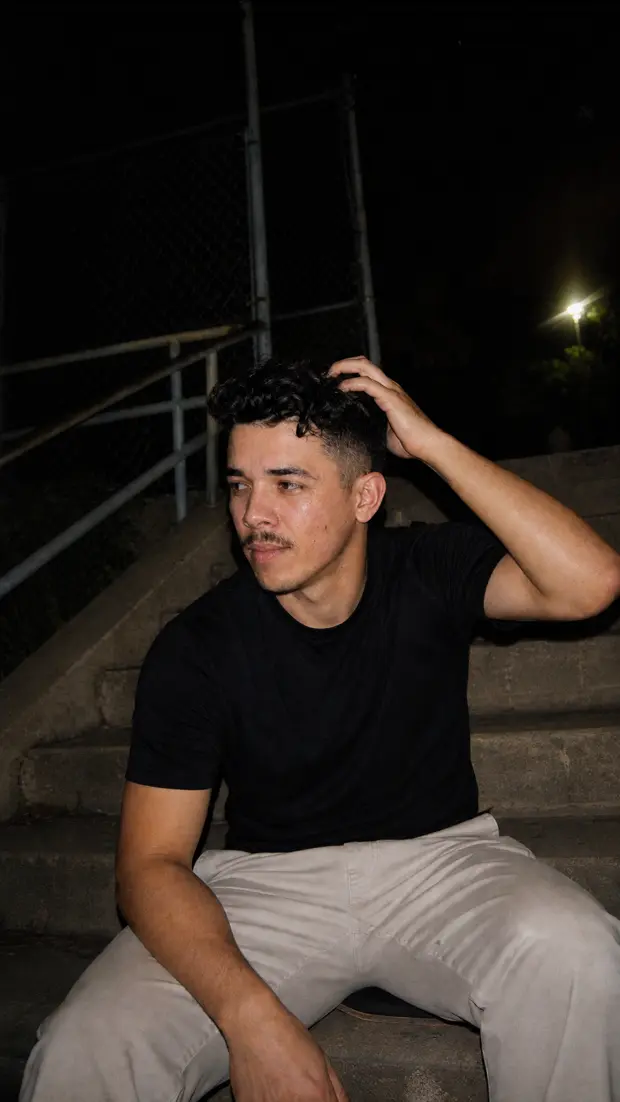 The same AI creator sitting on concrete steps at night